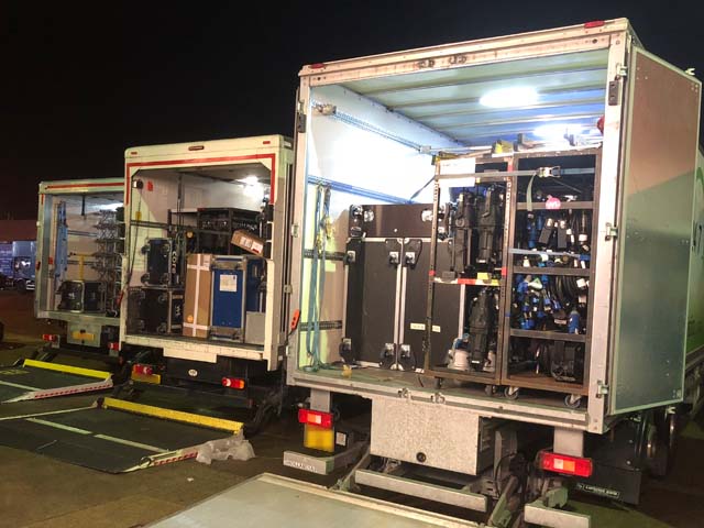 Nighttime photograph of fully loaded trucks with back door open